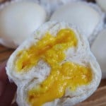 A halved custard bun held by a hand with overlay text that says Steamed custard buns