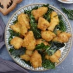 a plate of Taiwanese popcorn chicken with fried basil leaves.