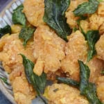 a plate of popcorn chicken with fried basil leaves.