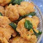 a plate of fried chicken with fried basil leaves with overlay text that says "popcorn chicken".