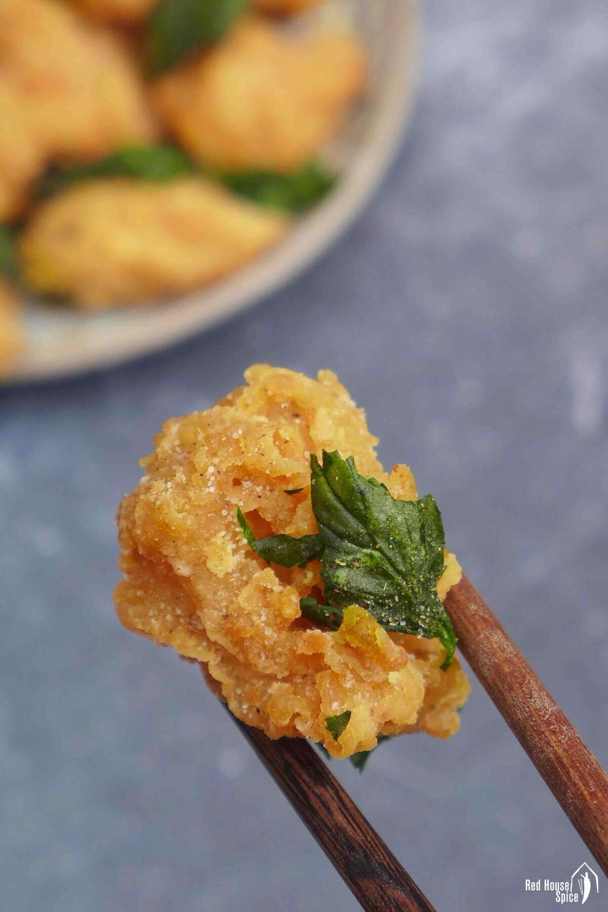 chopsticks picking up a piece of popcorn chicken.